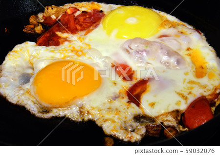 Fried eggs from two chicken eggs. Cooked with tomatoes. The yolks have a different shade of yellow. 59032076