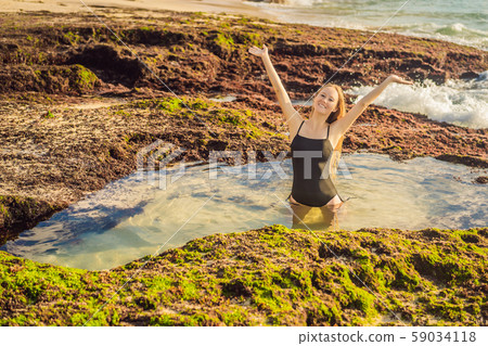 Young woman tourist on Pantai Tegal Wangi Beach sitting in a bath of sea water, Bali Island 59034118
