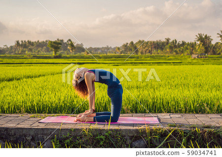 Young woman practice yoga outdoor in rice fields in the morning during wellness retreat in Bali Young woman practice yoga outdoor in rice fields in the morning during wellness retreat in Bali 59034741