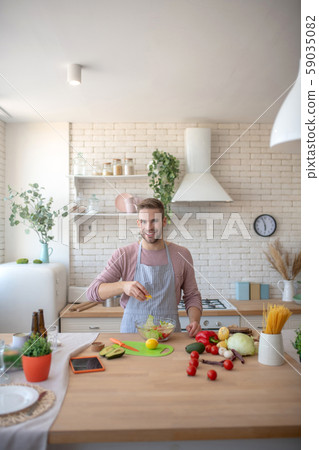 Man standing in his spacious kitchen and cooking 59035082