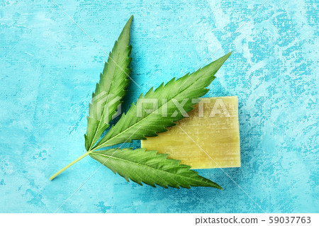 A cannabis leaf with homemade hemp soap, shot from the top on a turquoise blue background 59037763