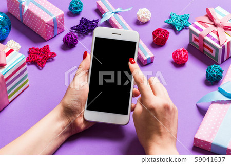 Top view of phone in female hand on festive purple Top view of phone in female hand on festive purple 59041637