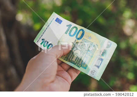 Male hand holding 100 hundredth euro banknote 59042012