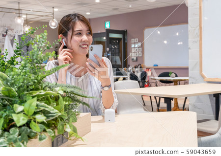 Young woman listening to music with a wireless earphone with a smile during the break 59043659