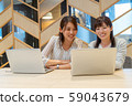 Two young women working with a smile towards the computer 59043679