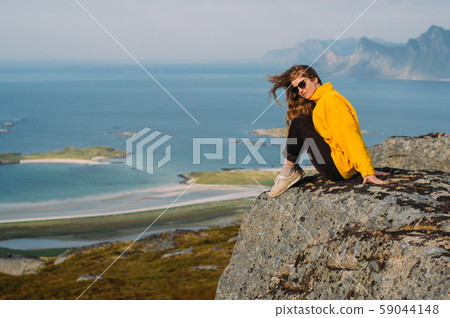 Girl in yellow jacket stitting on stone  59044148