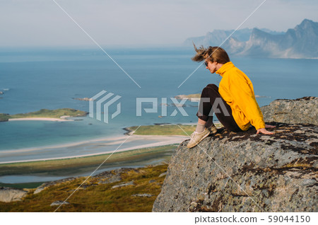 Girl in yellow jacket stitting on stone 59044150