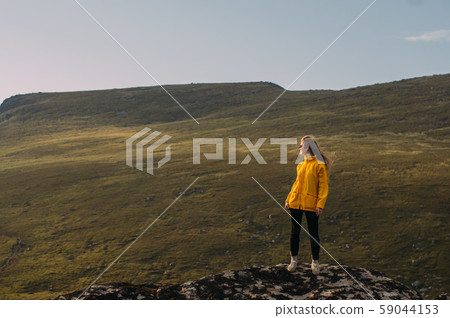 Girl in yellow jacket staying in mountains Girl in yellow jacket staying in mountains 59044153
