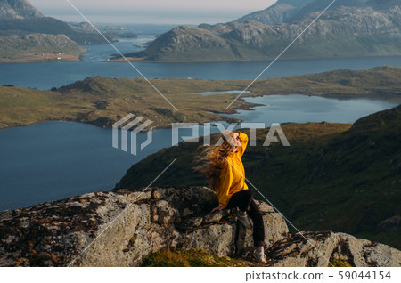 Girl in yellow jacket stitting on stone Girl in yellow jacket stitting on stone 59044154
