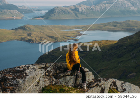Girl in yellow jacket stitting on stone 59044156