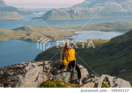 Girl in yellow jacket stitting on stone  59044157