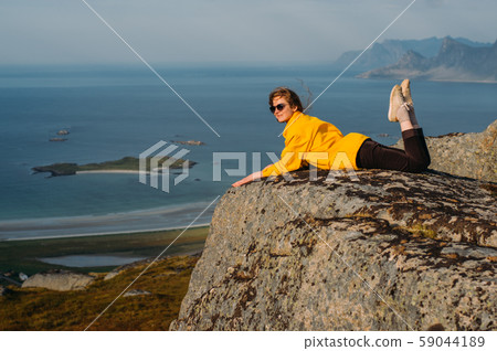 Smiling girl in yellow jacket and sunglasses lies 59044189