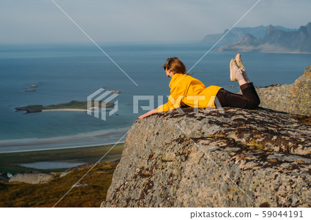 Girl in yellow jacket and sunglasses lies on stone 59044191