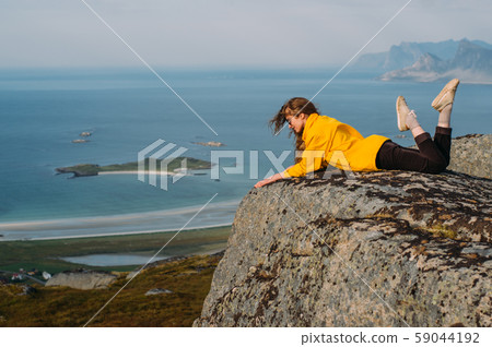 Smiling girl in yellow jacket and sunglasses lies 59044192