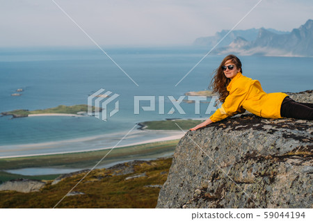 Smiling girl in yellow jacket and sunglasses lies 59044194