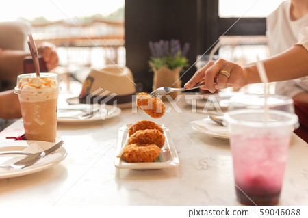 Woman hand holding fork taking food with drink on table. 59046088