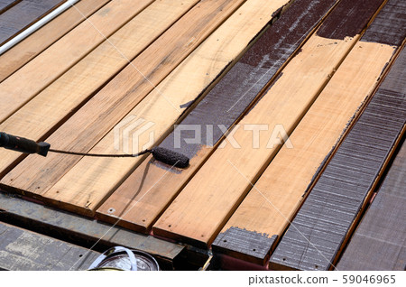 Worker painting with paint roller on wood floor Worker painting with paint roller on wood floor 59046965