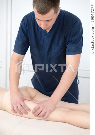 Portrait of a masseur male doing hip massage to a girl in a spa salon. Massage and body care concept Portrait of a masseur male doing hip massage to a girl in a spa salon. Massage and body care concept 59047277