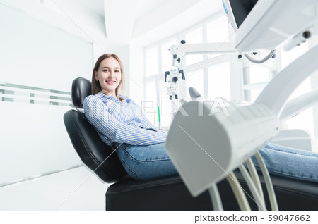 Portrait of an attractive smiling girl blonde in a dental chair. Happy customer dental cabinet 59047662