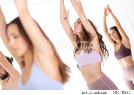 Group of young sporty attractive women in yoga studio, practicing yoga lesson with instructor 59048581