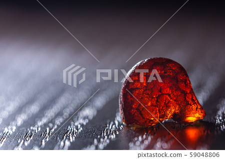 Natural amber. A piece of yellow transparent natural amber on large piece of dark stoned wood. Natural amber. A piece of yellow transparent natural amber on large piece of dark stoned wood. 59048806