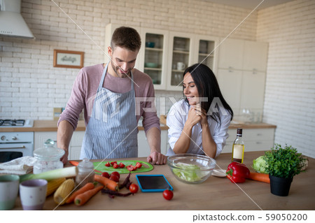 Wife watching husband slicing tomatoes for omelet Wife watching husband slicing tomatoes for omelet 59050200