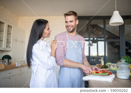 Beaming husband cooking breakfast for his lovely wife 59050202
