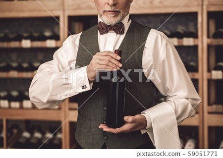 Sommelier Concept. Senior man standing with botle of wine confident close-up Sommelier Concept. Senior man standing with botle of wine confident close-up 59051771