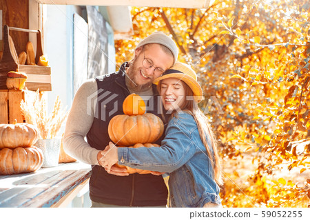 Halloween Preparaton Concept. Young couple decorating house with pumpkins hugging smiling happy Halloween Preparaton Concept. Young couple decorating house with pumpkins hugging smiling happy 59052255