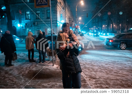 Young adult couple walking on snow covered sidewalk 59052318