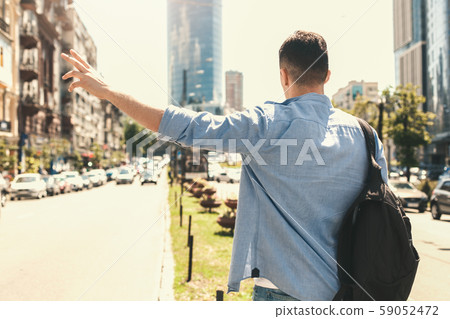 Outdoors Leisure. Stylish guy traveler standing near road hitchhiking back view Outdoors Leisure. Stylish guy traveler standing near road hitchhiking back view 59052472