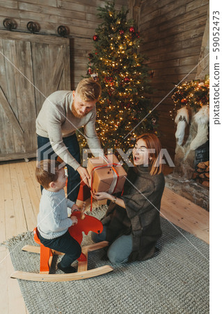 Young caucasian family mom dad son near fireplace christmas tree Young caucasian family mom dad son near fireplace christmas tree 59052473