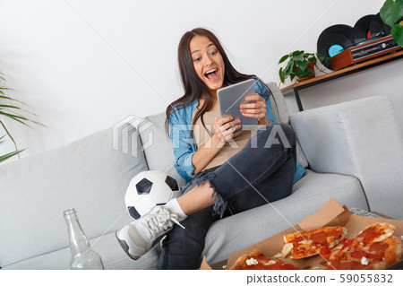 Young woman sport fan watching football match on digital tablet Young woman sport fan watching football match on digital tablet 59055832