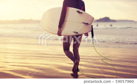 Surfer woman walking with surfboard on the beach 59057960