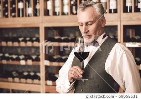 Sommelier Concept. Senior man standing holding glass smelling wine closed eyes concentrated Sommelier Concept. Senior man standing holding glass smelling wine closed eyes concentrated 59058531