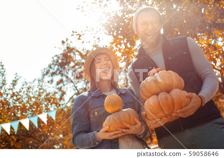 Young adult friends laughing and holding ripe pumpkin in hands 59058646