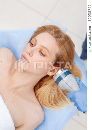 Cosmetology Service. Young woman at beauty clinic lying while doctor using body contouring coolwaves Cosmetology Service. Young woman at beauty clinic lying while doctor using body contouring coolwaves 59058762