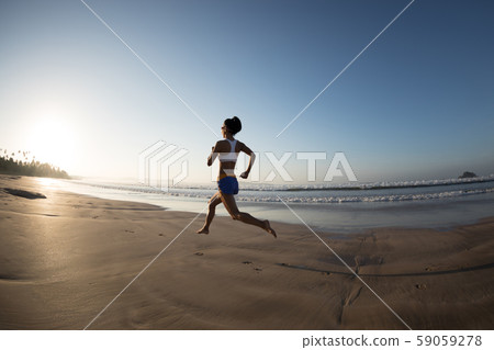 young fitness woman running at sunrise beach 59059278
