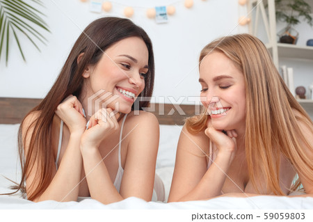 Friends together at home lying on bed laughing cheerful at joke close-up 59059803