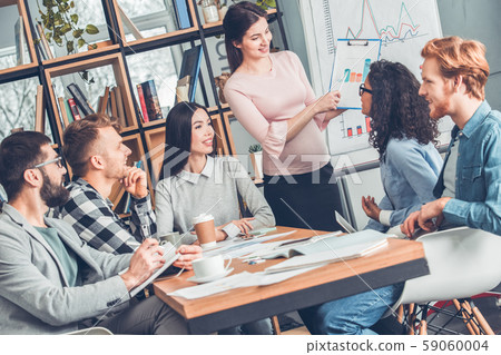 Startupers working together at office sitting smiling looking at pregnant woman standing showing 59060004