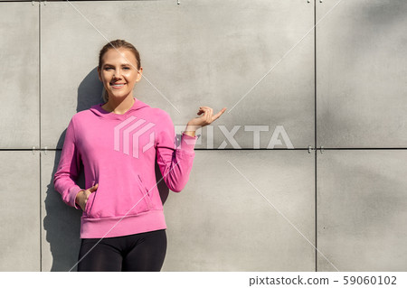 Healthy Lifestyle. Young woman standing isolated leaning on wall outdoors autumn season pointing at 59060102