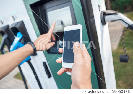 Young adult man using smartphone and paying for charging electric car Young adult man using smartphone and paying for charging electric car 59060328