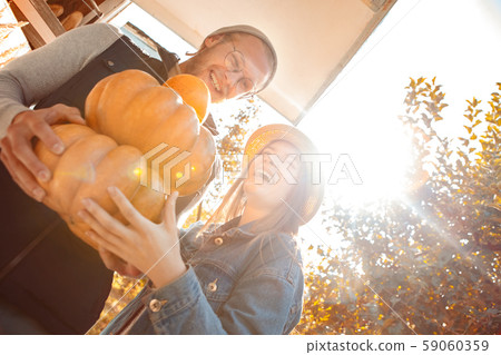 Halloween Preparaton Concept. Young couple decorating house with pumpkins laughing happy in sunlight 59060359