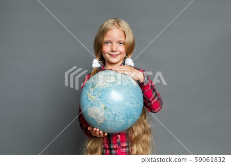 Little girl with ponytails standing isolated on grey with globe travel the world smiling positive 59061832