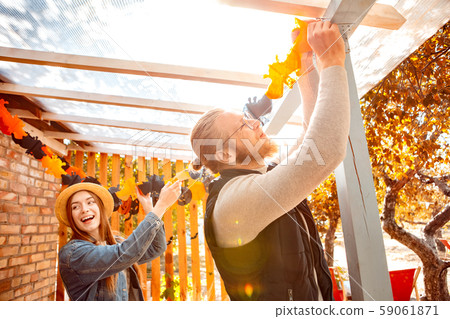 Young adult woman and man hanging paper garlands for halloween Young adult woman and man hanging paper garlands for halloween 59061871
