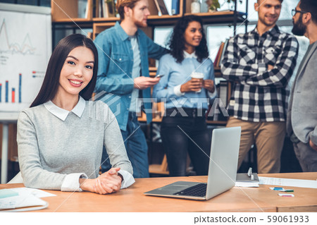 Startupers working together at office woman sitting at table with laptop looking camera joyful 59061933