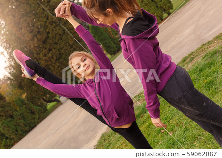 Outdoors leisure. Sister helping little girl doing pirouette in the autumn park looking camera proud Outdoors leisure. Sister helping little girl doing pirouette in the autumn park looking camera proud 59062087