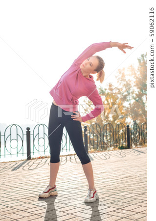 Healthy Lifestyle. Young woman warming up outdoors autumn season bending to the left thoughtful 59062116