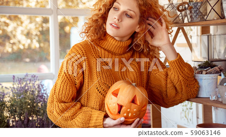 Woman holding carved pumpkin, preparing halloween celebration at home 59063146