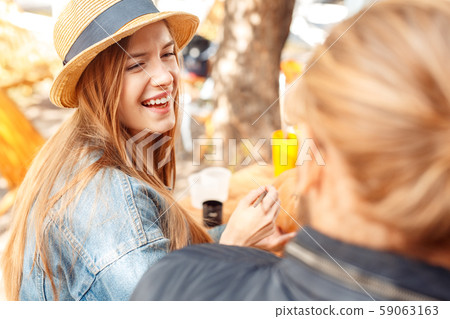 Halloween Preparaton Concept. Young couple sitting at table outdoors making jack-o'-lantern looking 59063163